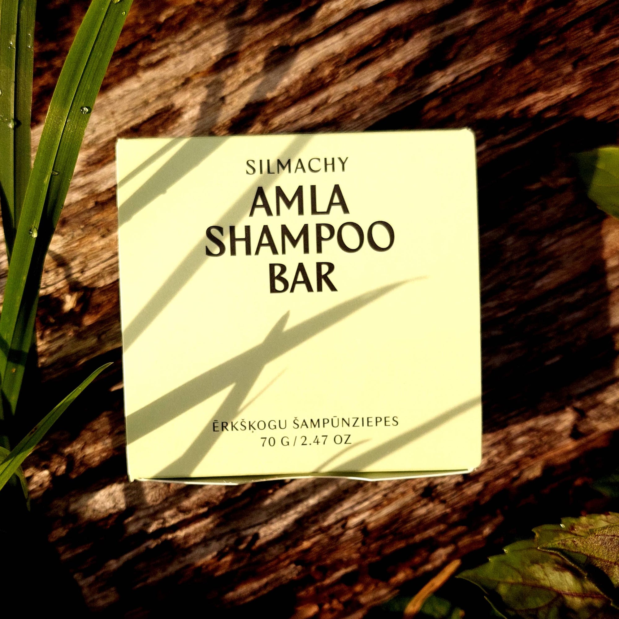 Amla Shampoo Bar packaging on a wooden surface with green leaves