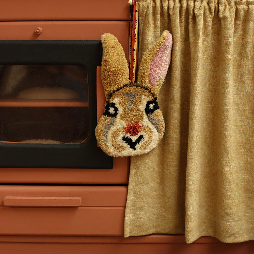 Decorative rabbit head hanging on a curtain in front of an orange oven.