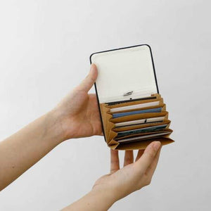 Person holding a wallet with multiple card slots against a plain background