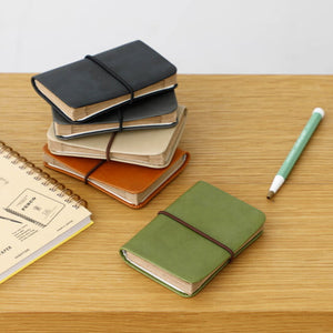 Stack of small notebooks and a pen on a wooden surface