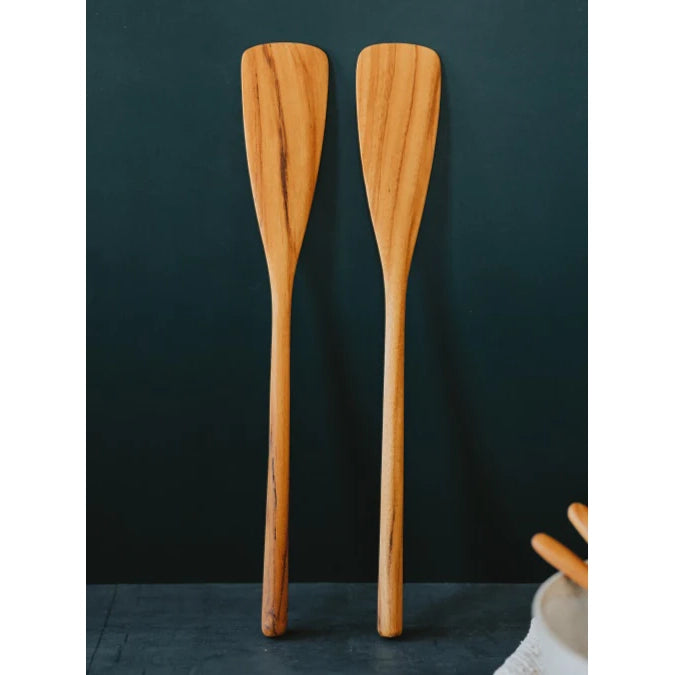 Two wooden cooking paddles standing upright against a dark background.
