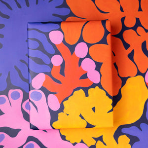 Colorful abstract patterned paper with orange, pink, and yellow shapes on a dark background