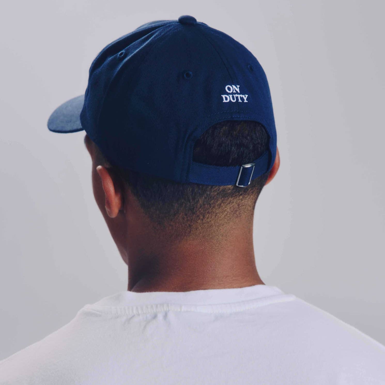 Person wearing a navy blue cap with 'ON DUTY' text on a plain background