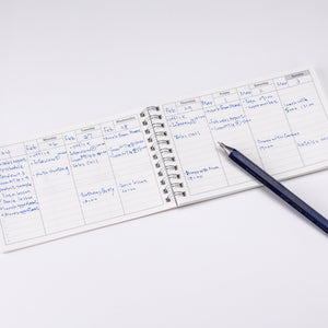 Small notepad with handwritten notes on a white surface with a pen next to it.