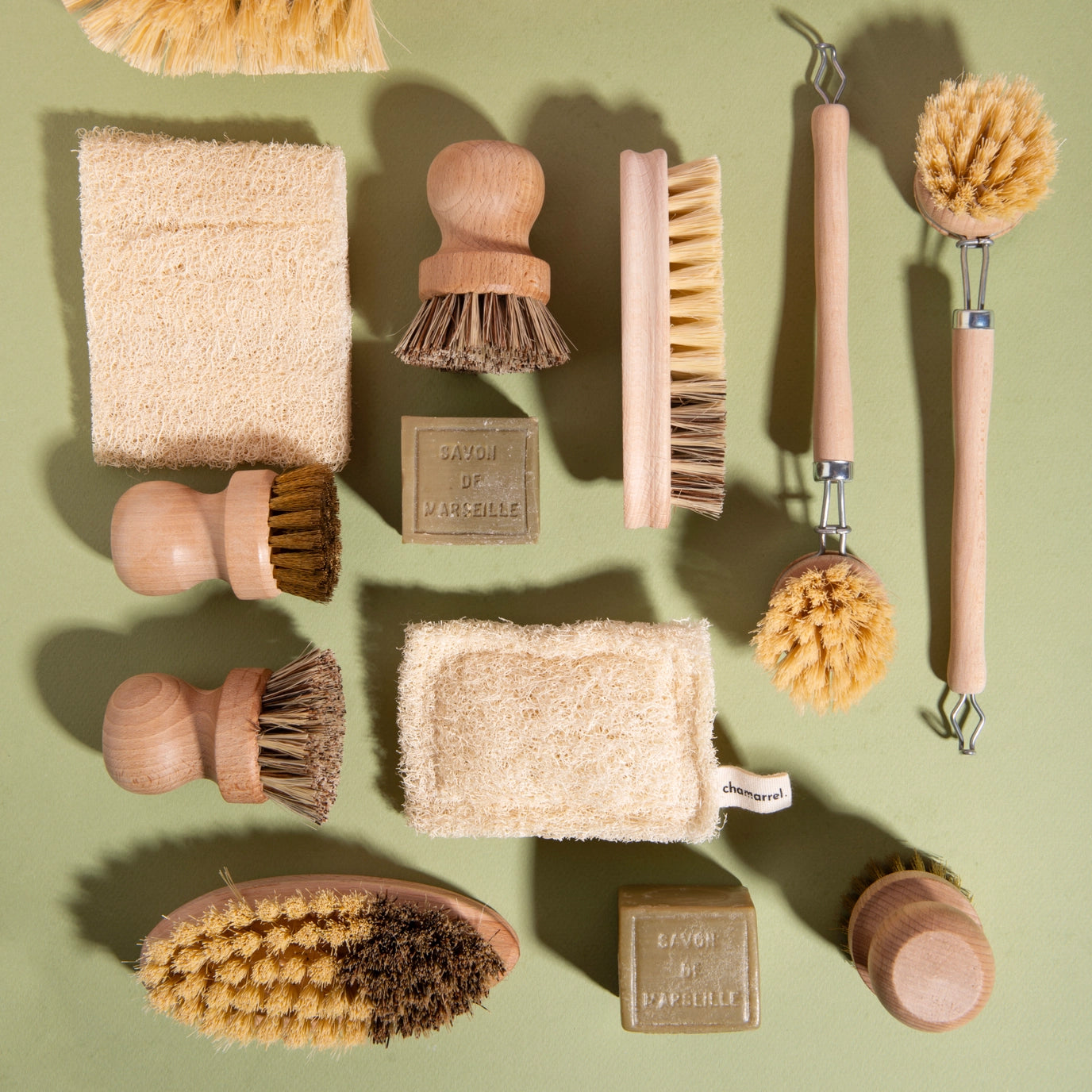 Collection of natural cleaning tools and soap bars on a green background