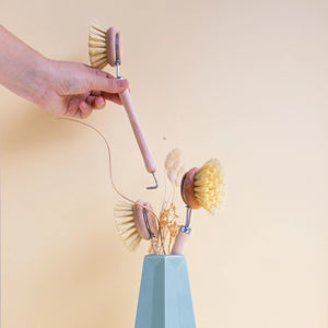 Set of dishwashing brushes with a holder on a light yellow background