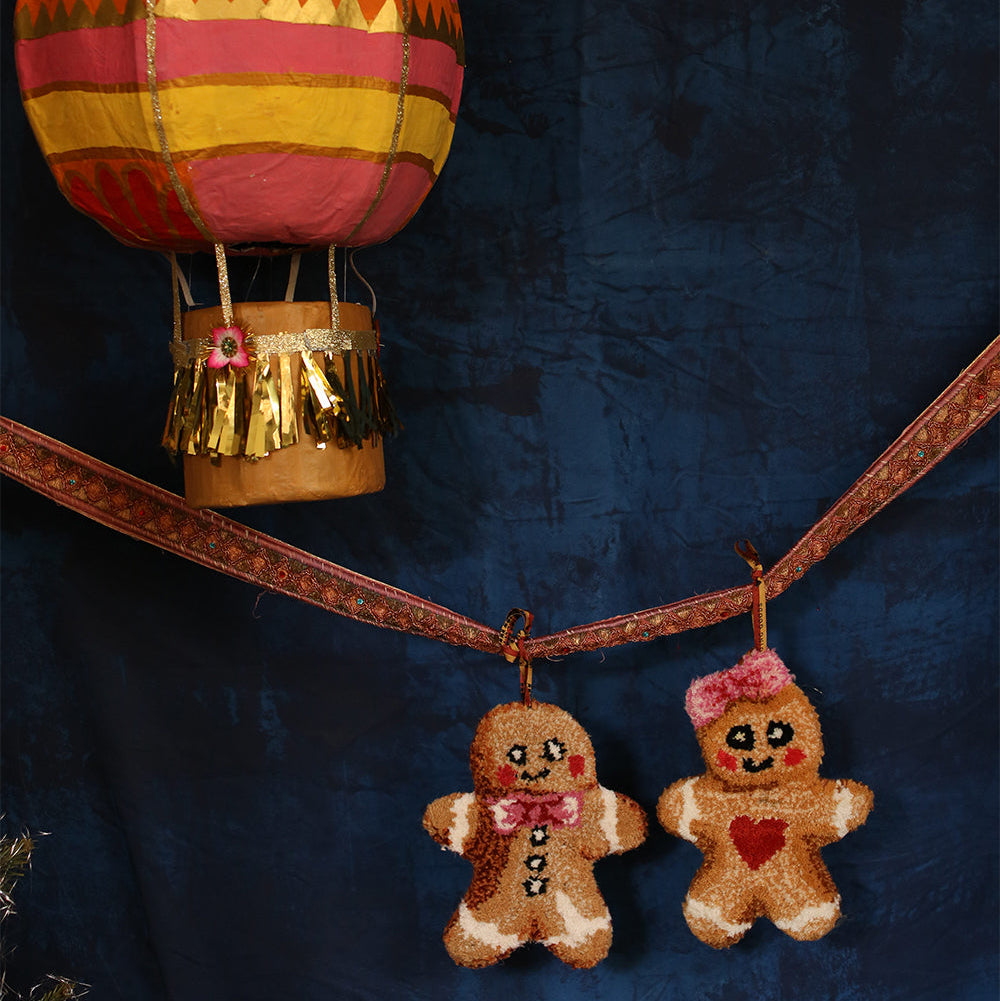 Decorative gingerbread man ornaments hanging from a hot air balloon against a dark blue background