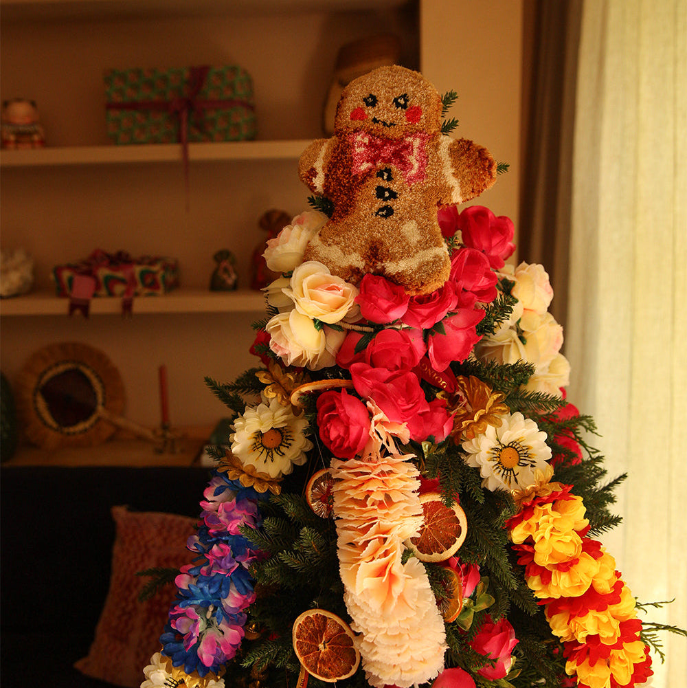 Decorative Christmas tree with gingerbread man and floral decorations in a home setting.