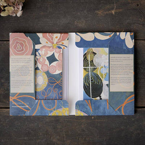 Open book with floral and abstract designs on a wooden surface