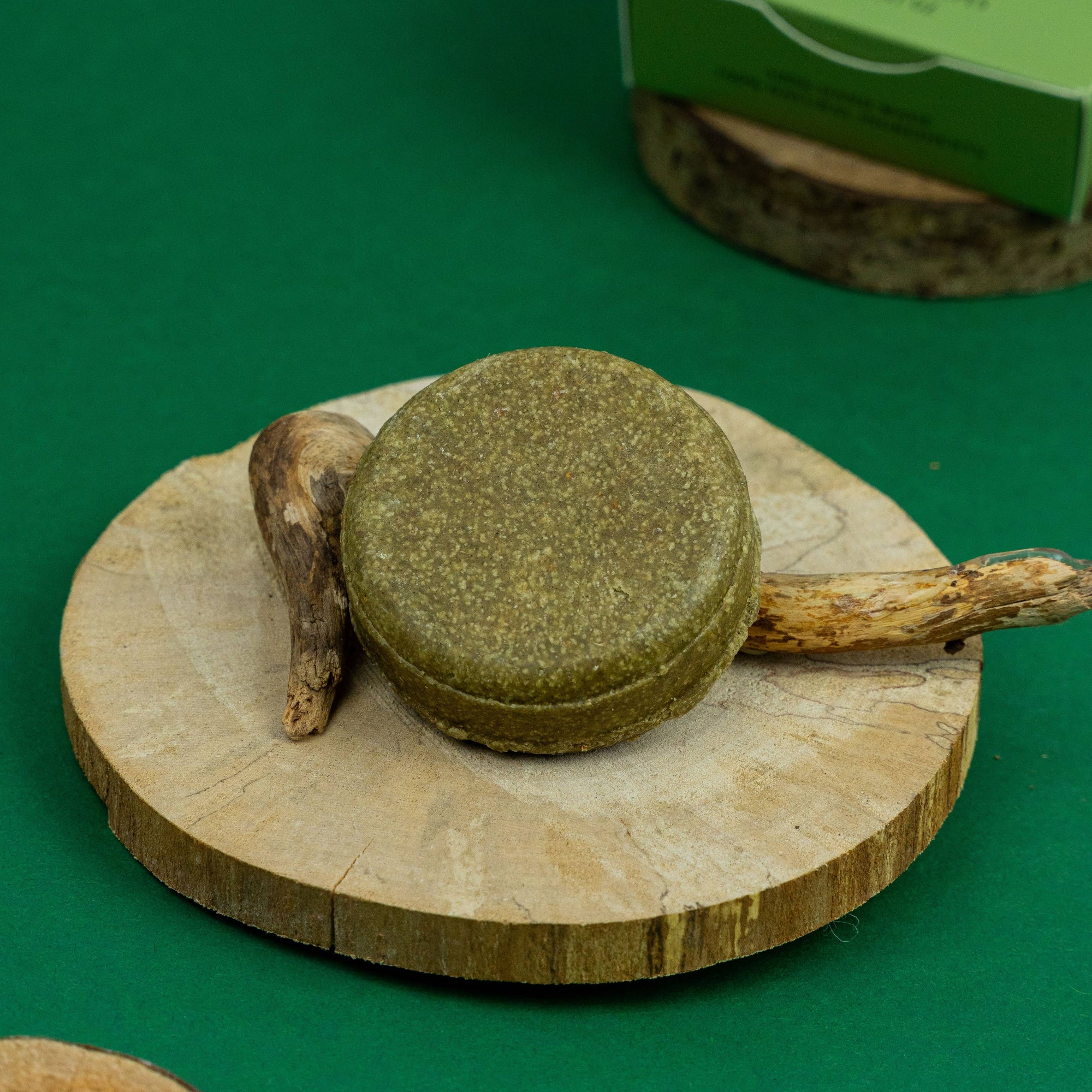 Green soap bar on a wooden coaster with a green background