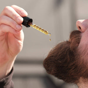 Person using a dropper to apply a liquid to their hair.