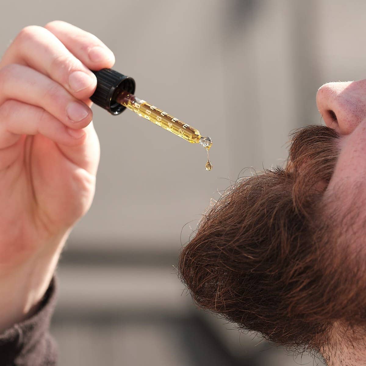 Person using a dropper to apply a liquid to their hair.