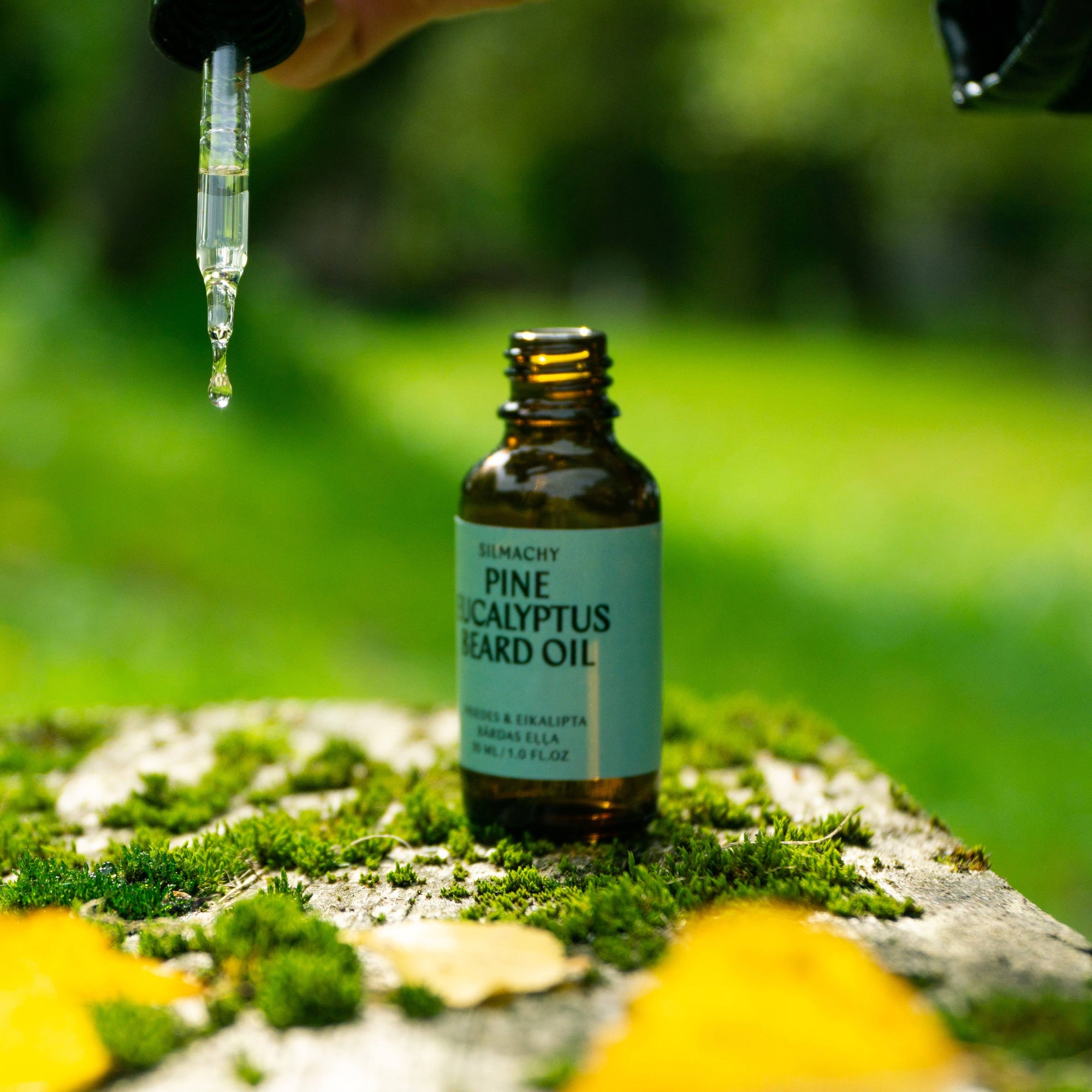 Bottle of pine eucalyptus beard oil with dropper on a natural background