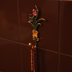 Decorative towel hook with floral design on a tiled wall