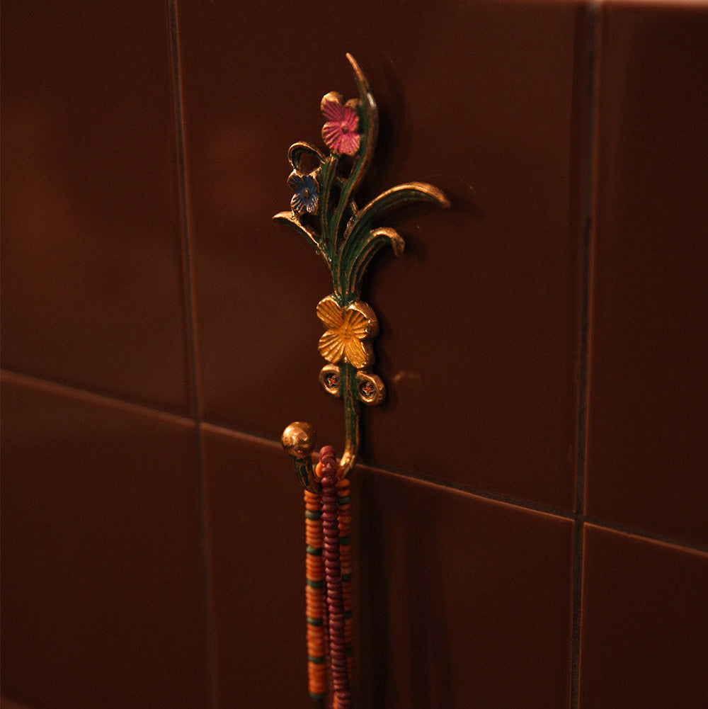 Decorative towel hook with floral design on a tiled wall
