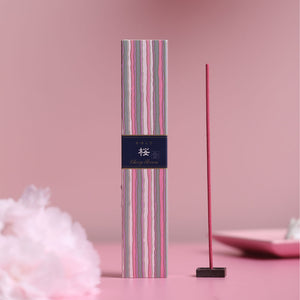 Incense stick with striped packaging on a pink background