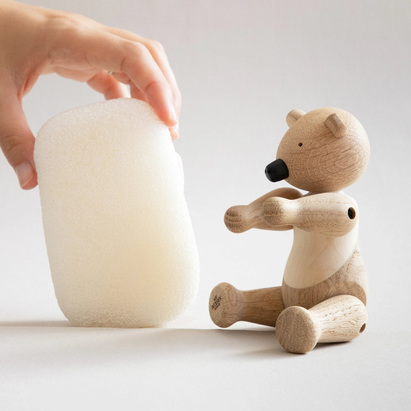Wooden bear toy next to a white ceramic item on a light background