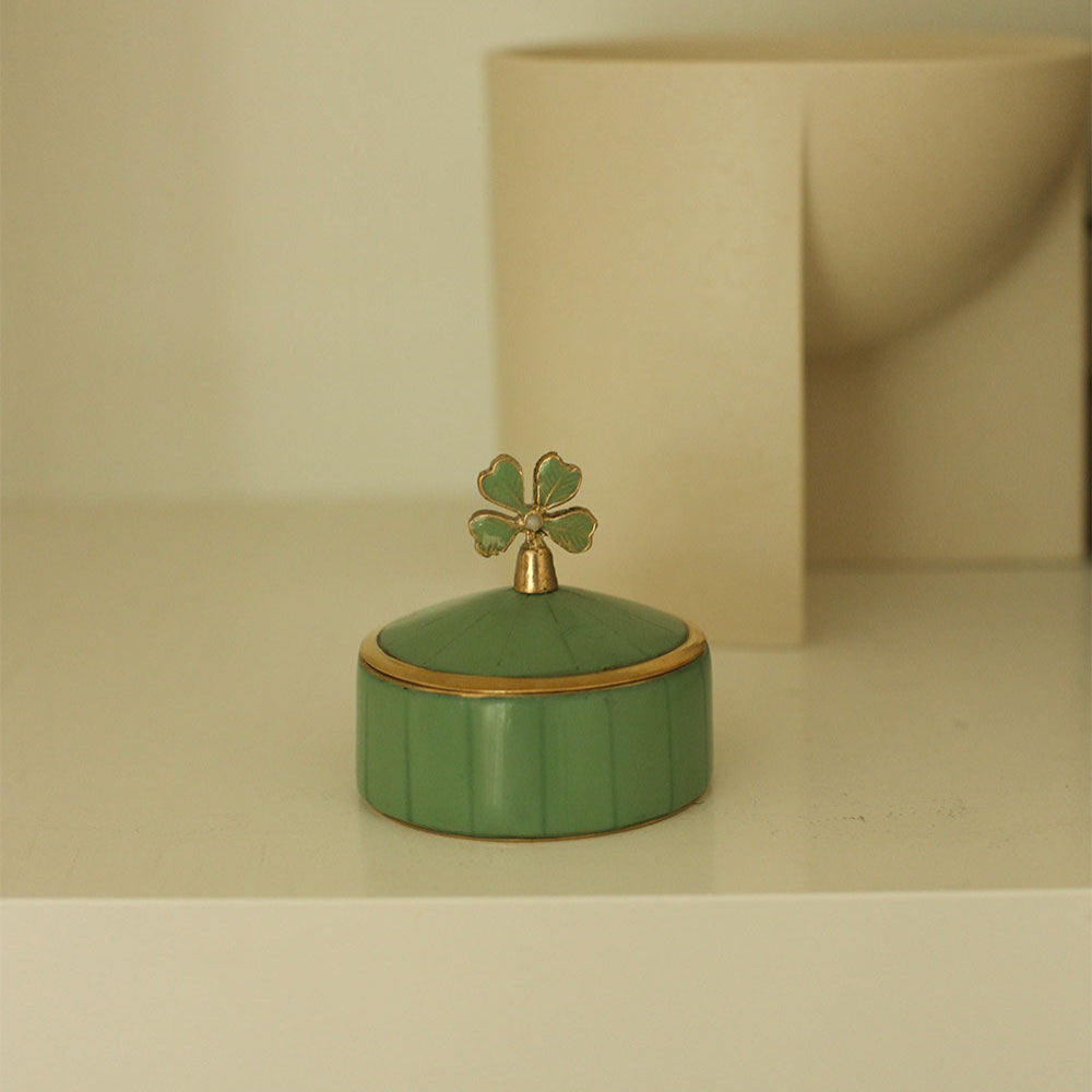 Green decorative box with a gold lid on a beige surface
