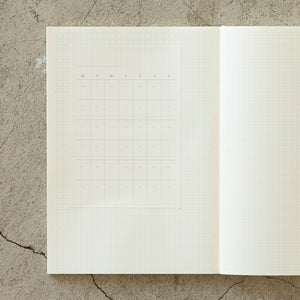 Open notebook with grid paper on a textured concrete surface