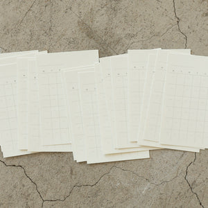 Multiple sheets of white paper with grid lines on a textured beige surface
