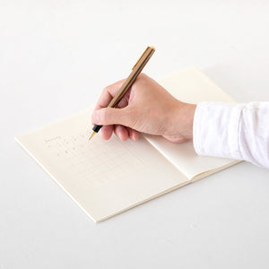Hand holding a pen over an open notebook on a white surface