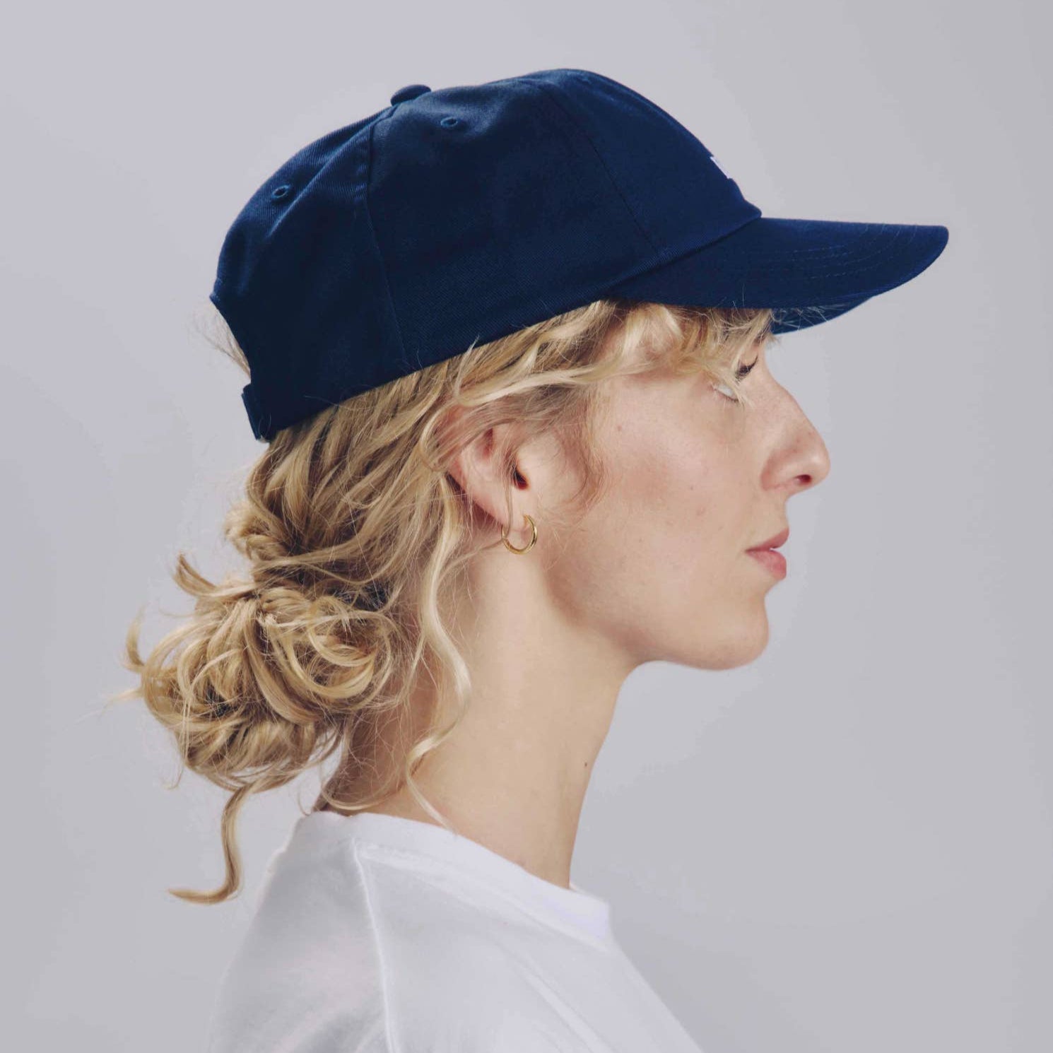 Person wearing a navy blue cap and white shirt against a light gray background