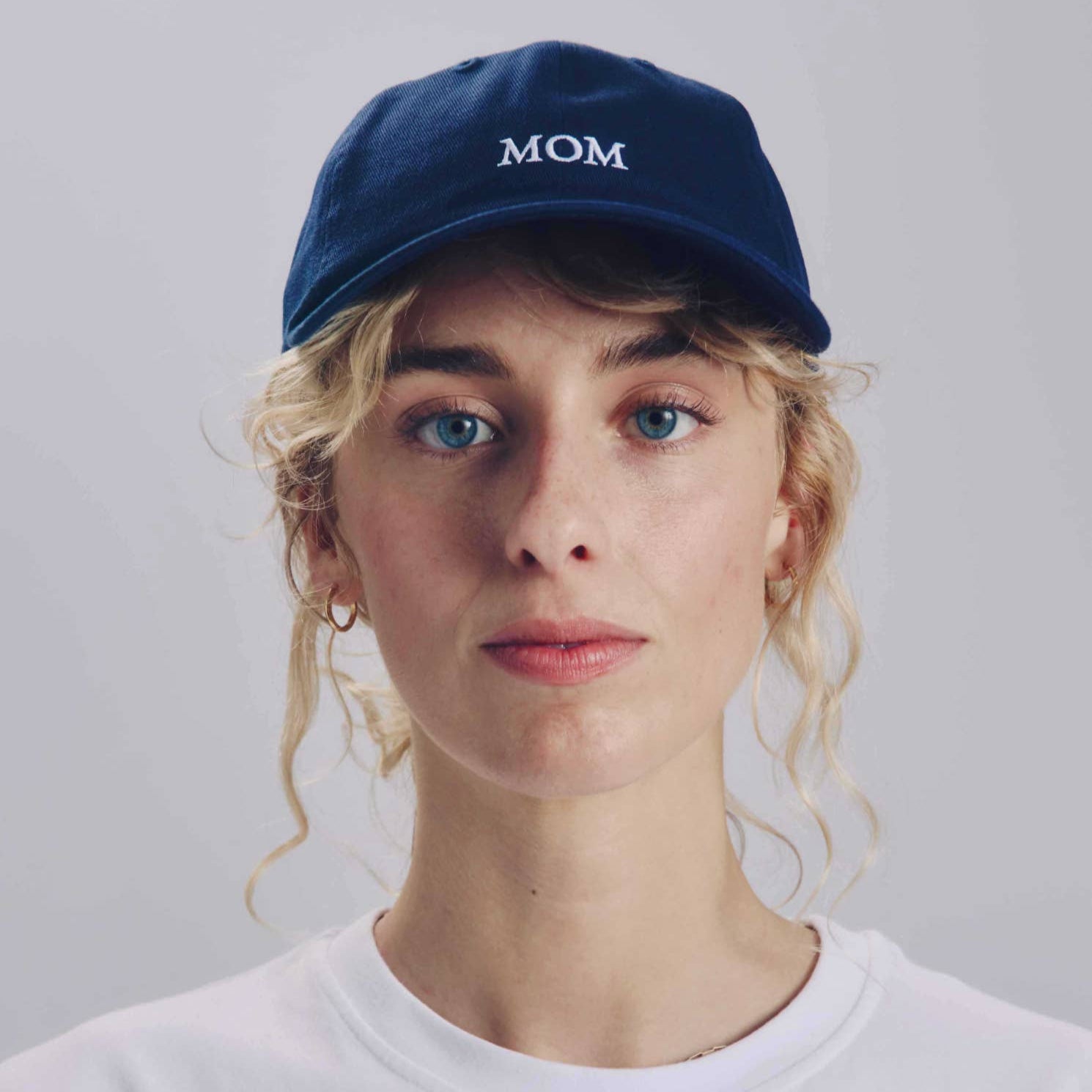 Person wearing a blue cap with 'MOM' text against a plain background