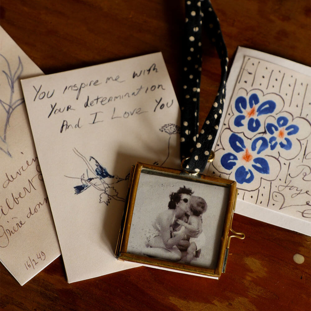 Small framed photo of a child holding a teddy bear on a wooden surface with handwritten notes and a decorative card.