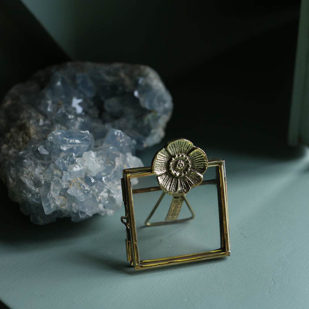 Gold brooch with floral design on a green surface next to a crystal