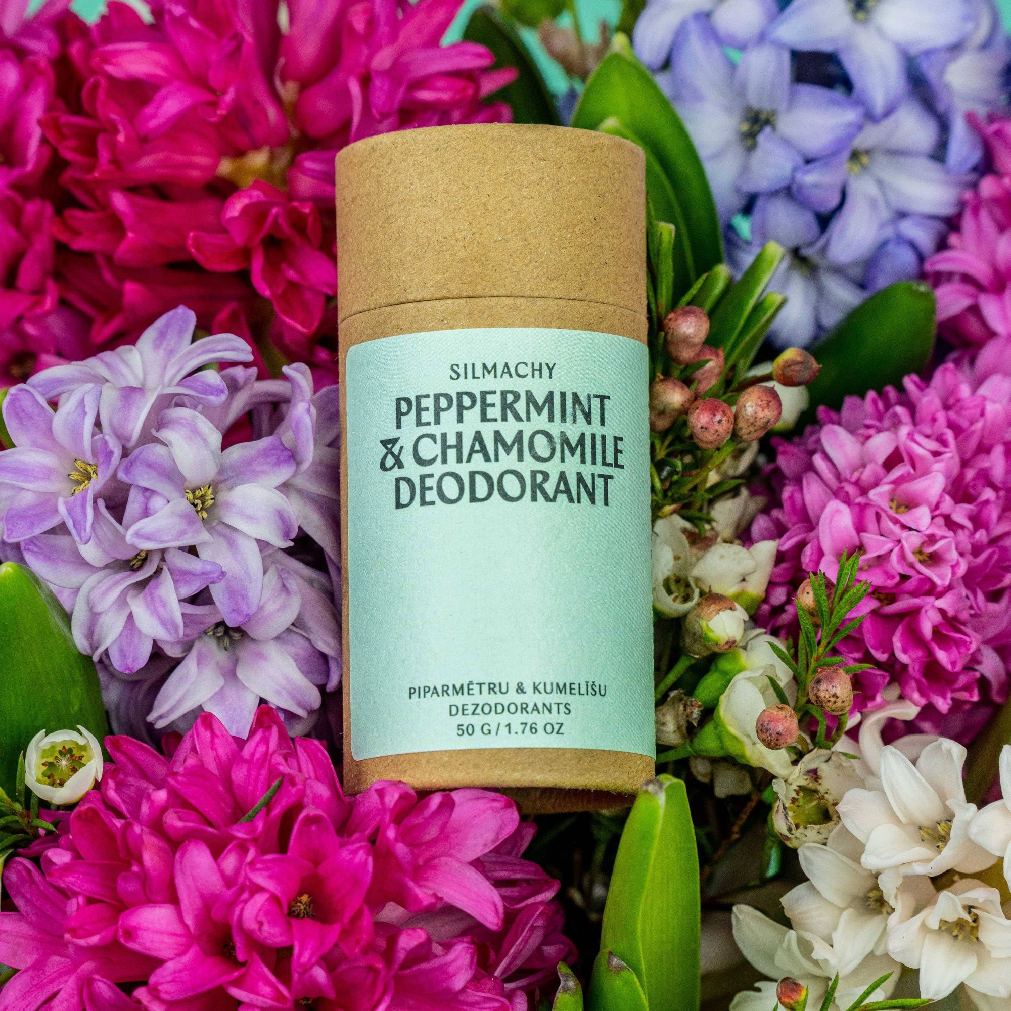 Silmacht Peppermint & Chamomile Deodorant surrounded by colorful flowers on a teal background