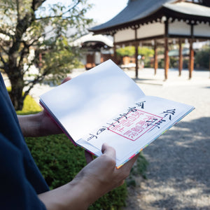 Person holding a book with Japanese text in a park setting