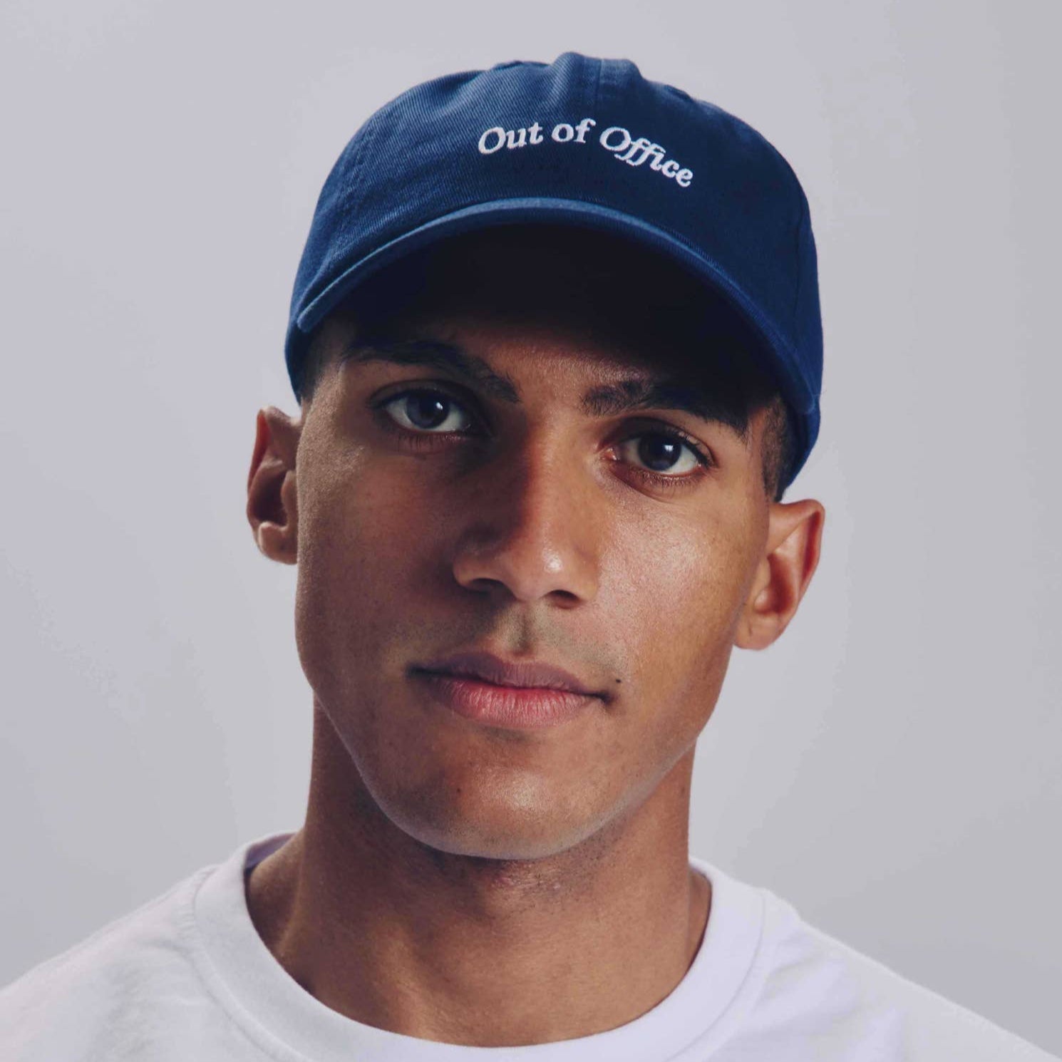 Person wearing a blue cap with 'Out of Office' text on a plain background