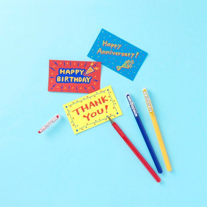 Colorful greeting cards with 'Happy Birthday', 'Thank You', and 'Happy Anniversary' text, along with markers on a blue background.