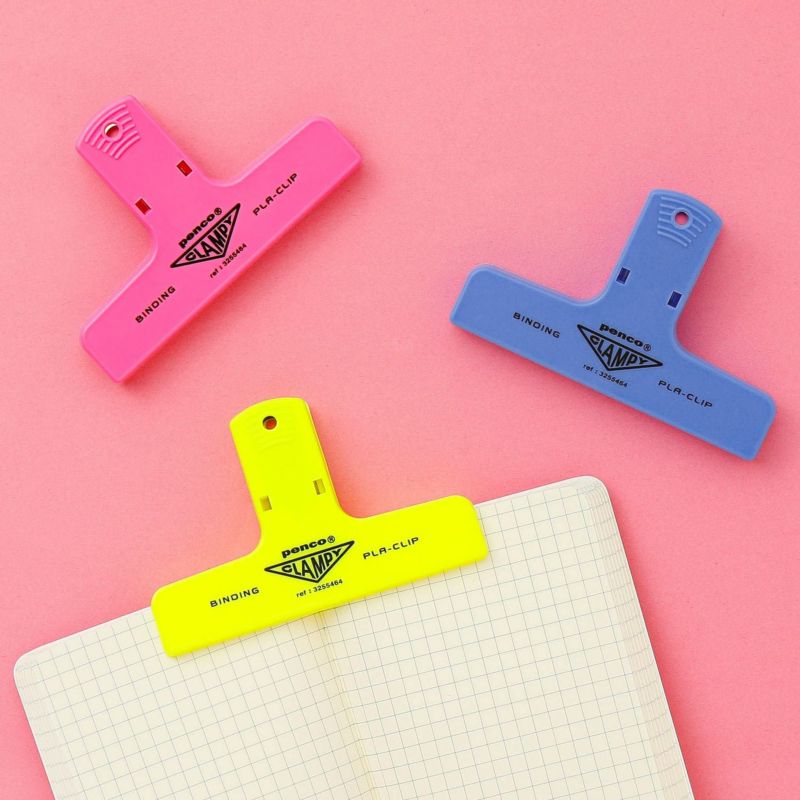 Three colorful binder clips on a pink background