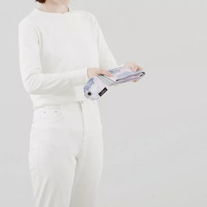 Person wearing a white outfit holding a product against a plain background
