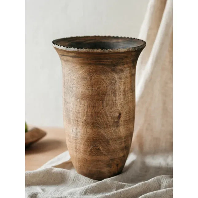 A handcrafted solid Mango Wood vase with a rustic finish, displayed against a soft-focus background.