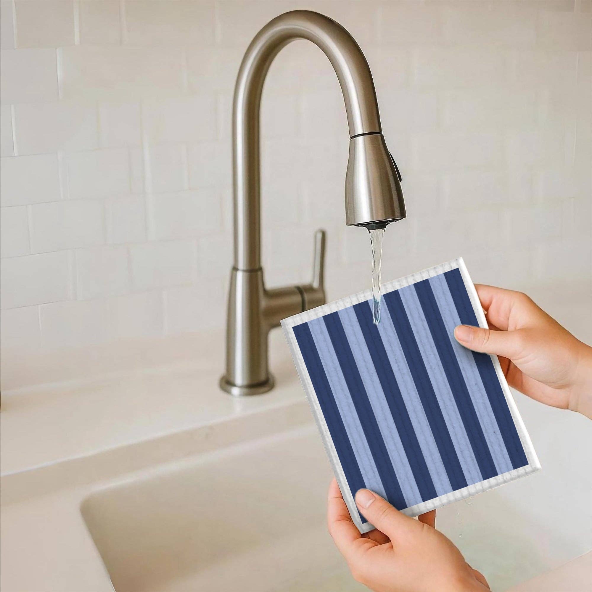 Person holding a striped towel under running water from a faucet.