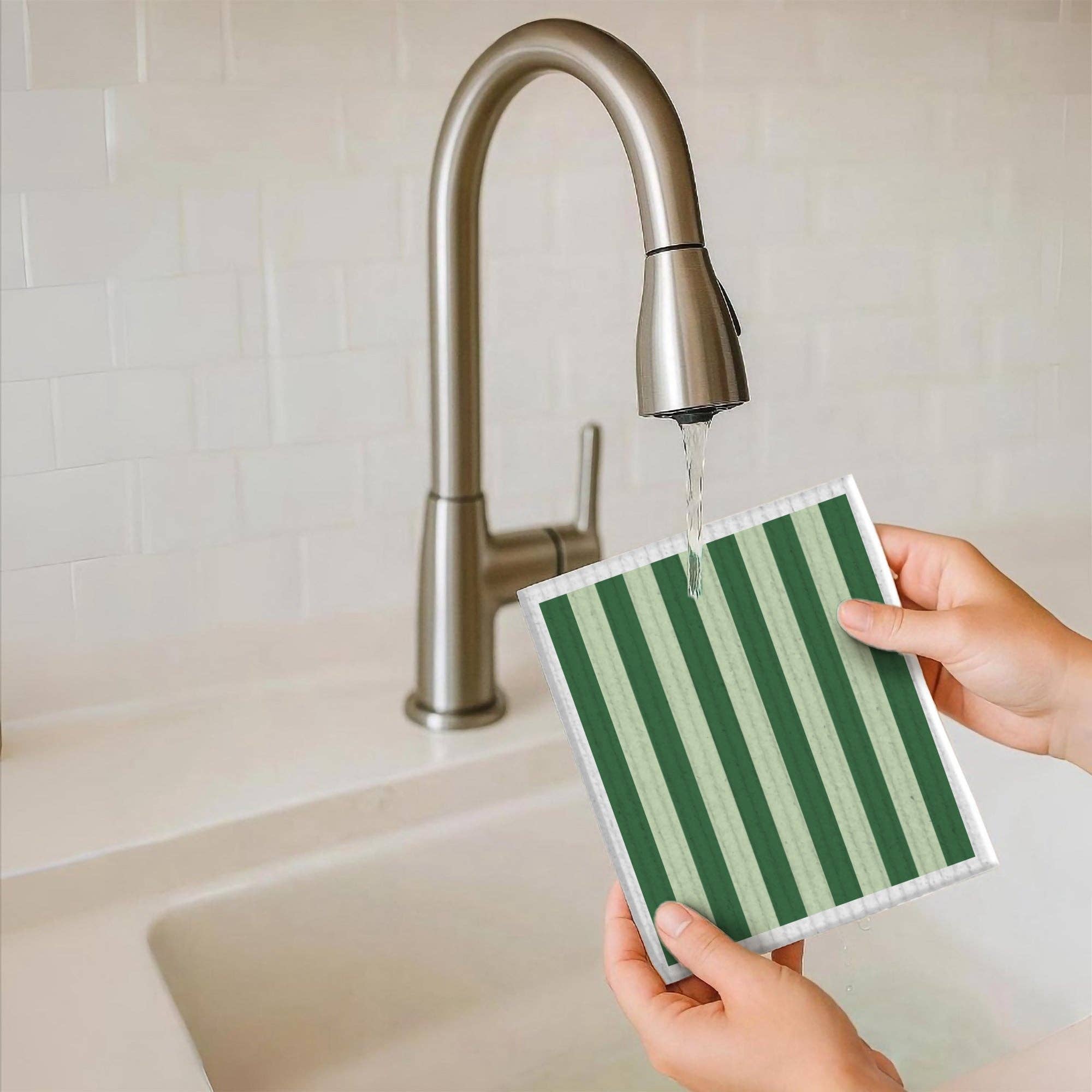 Person holding a green and white striped cloth under running water from a faucet.