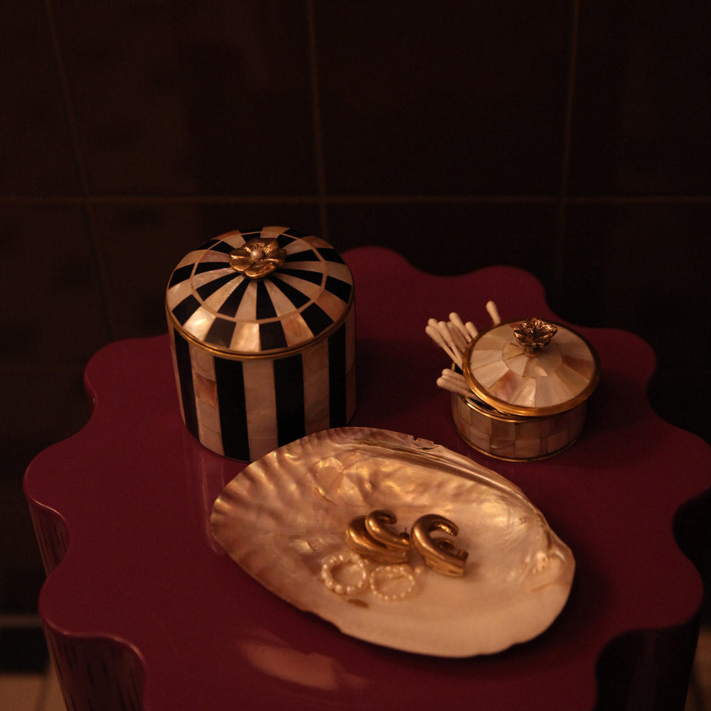 Decorative items including a striped container, a shell-shaped dish with gold accents, and a small box on a dark surface.