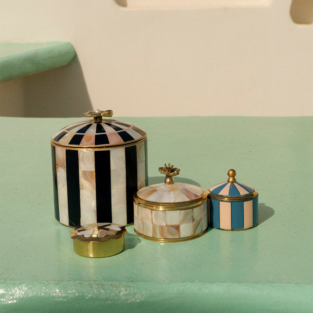 Three decorative jars with striped lids on a light green surface.