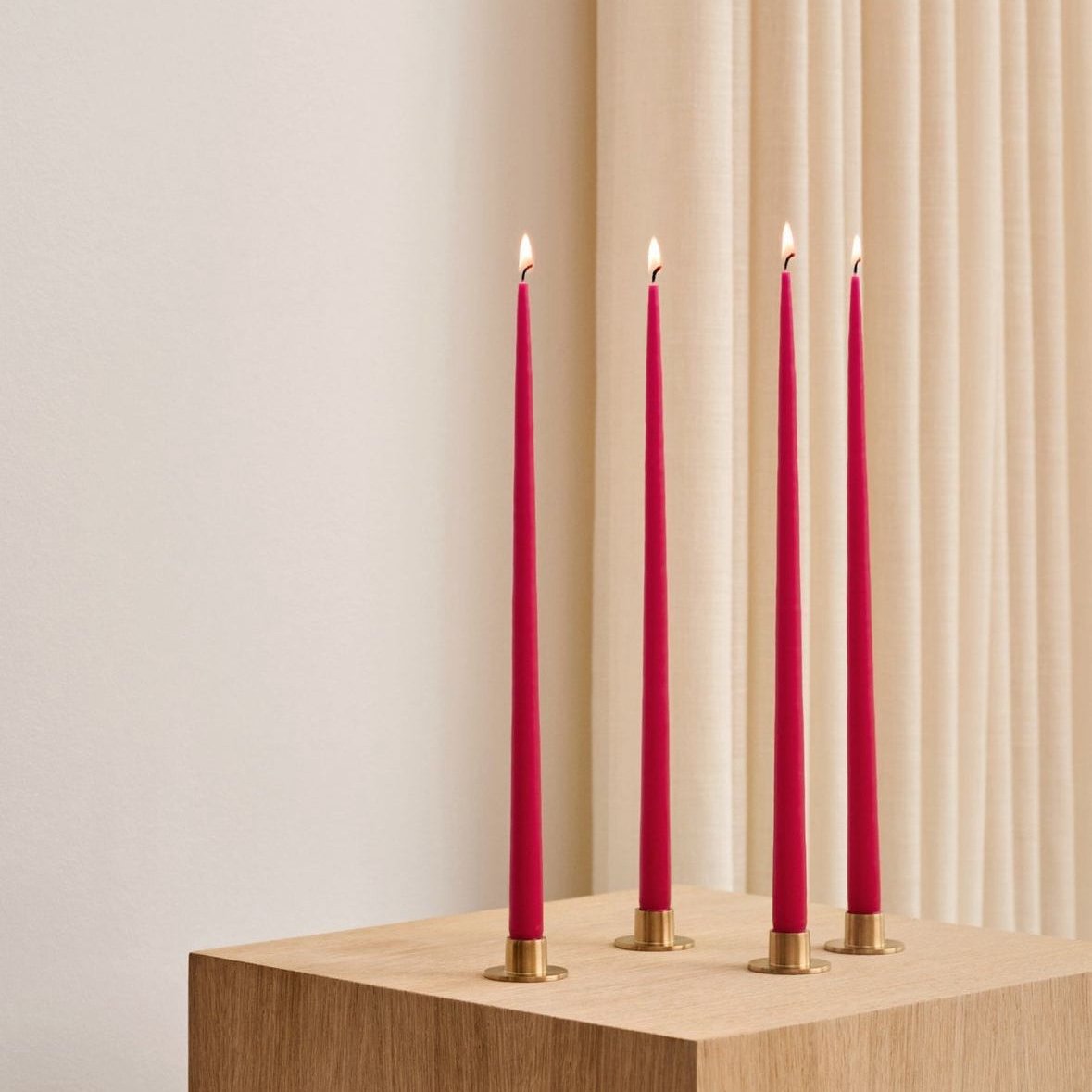 gold candle holders with red candles on a wooden pedestal