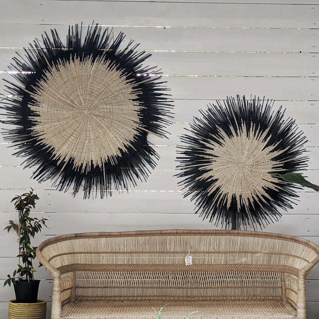 two handwoven sun circle wall decor hang on top a malawi sofa
