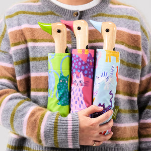 Person holding three colorful umbrellas with duck handles, each in a different patterned cover.
