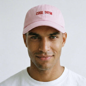Man wearing a pink cap with 'COOL MOM' text on a white background
