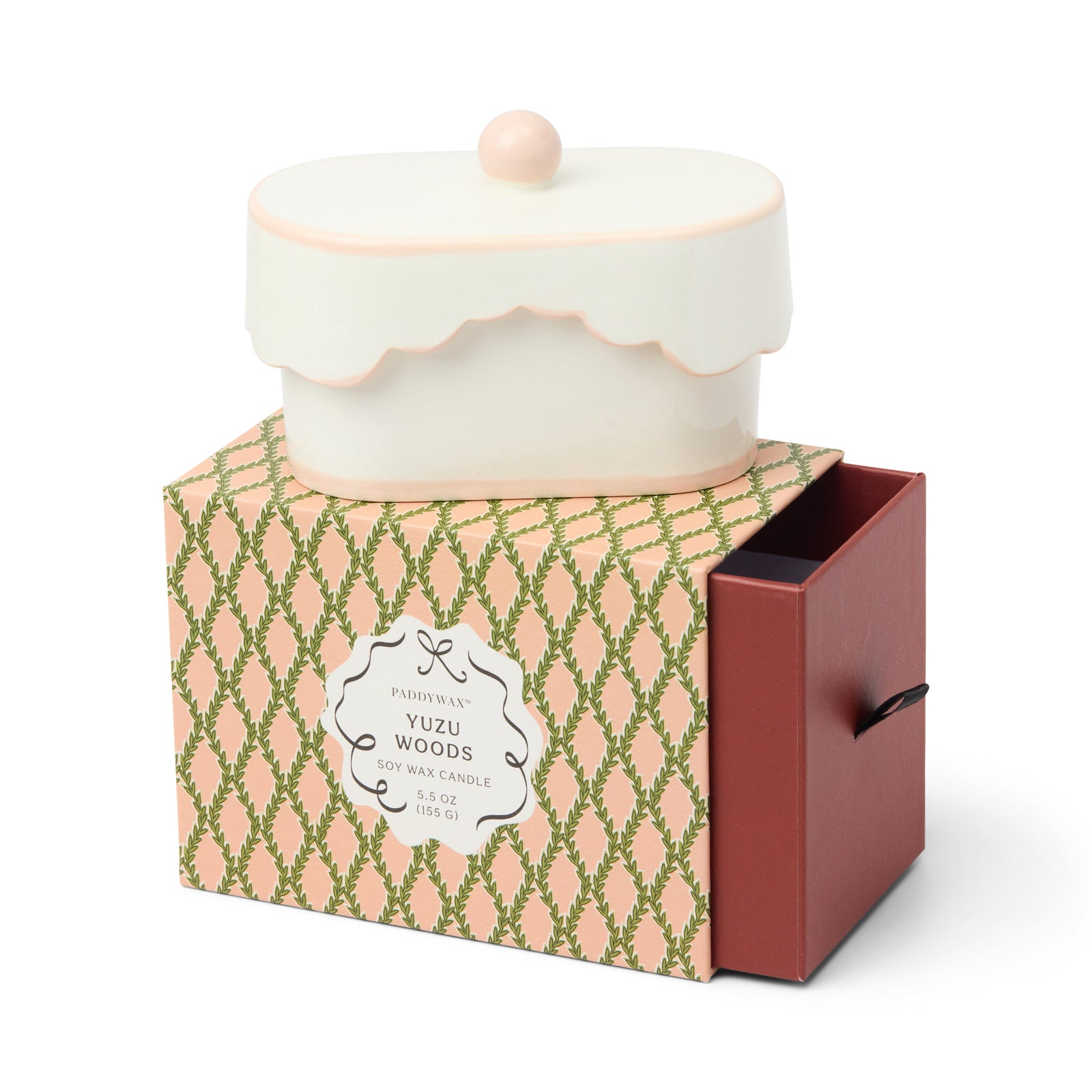 Candle in a decorative box with a pink and green pattern on a white background