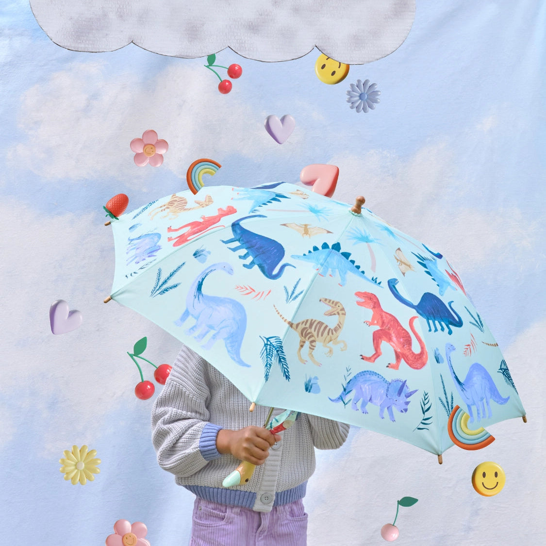Child holding a colorful umbrella with dinosaur design against a whimsical sky background