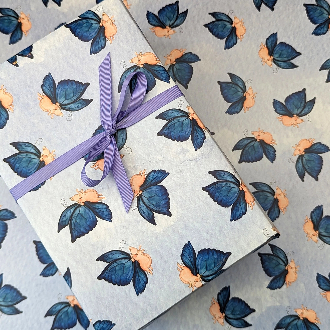 Gift box with blue butterfly pattern and purple ribbon on a matching background