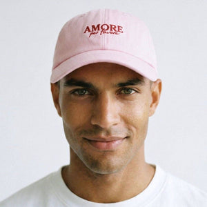 Man wearing a pink cap with 'AMORE' text on a white background