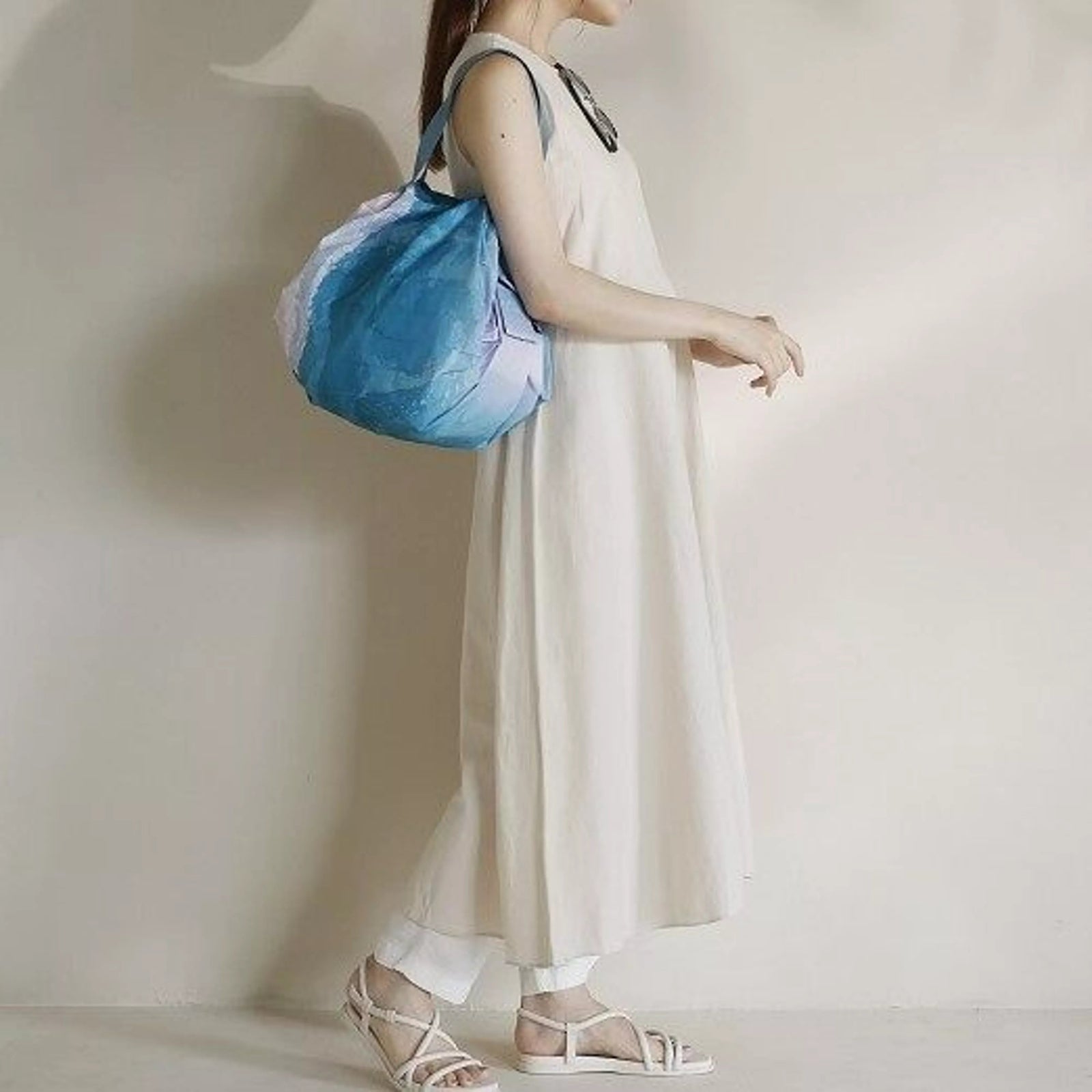 Person holding a blue bag against a plain background