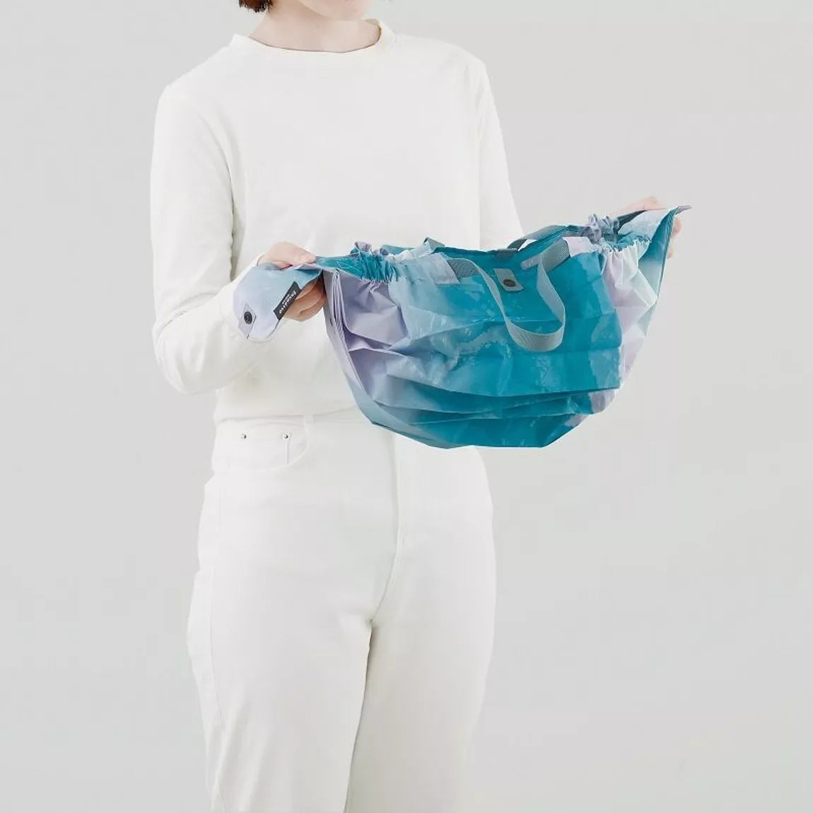 Person holding a blue bag against a plain background